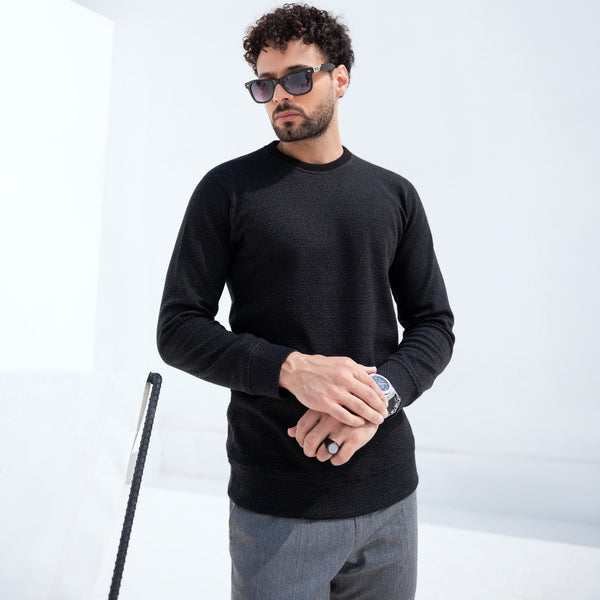man wearing black textured crewneck sweater and sunglasses in clean studio